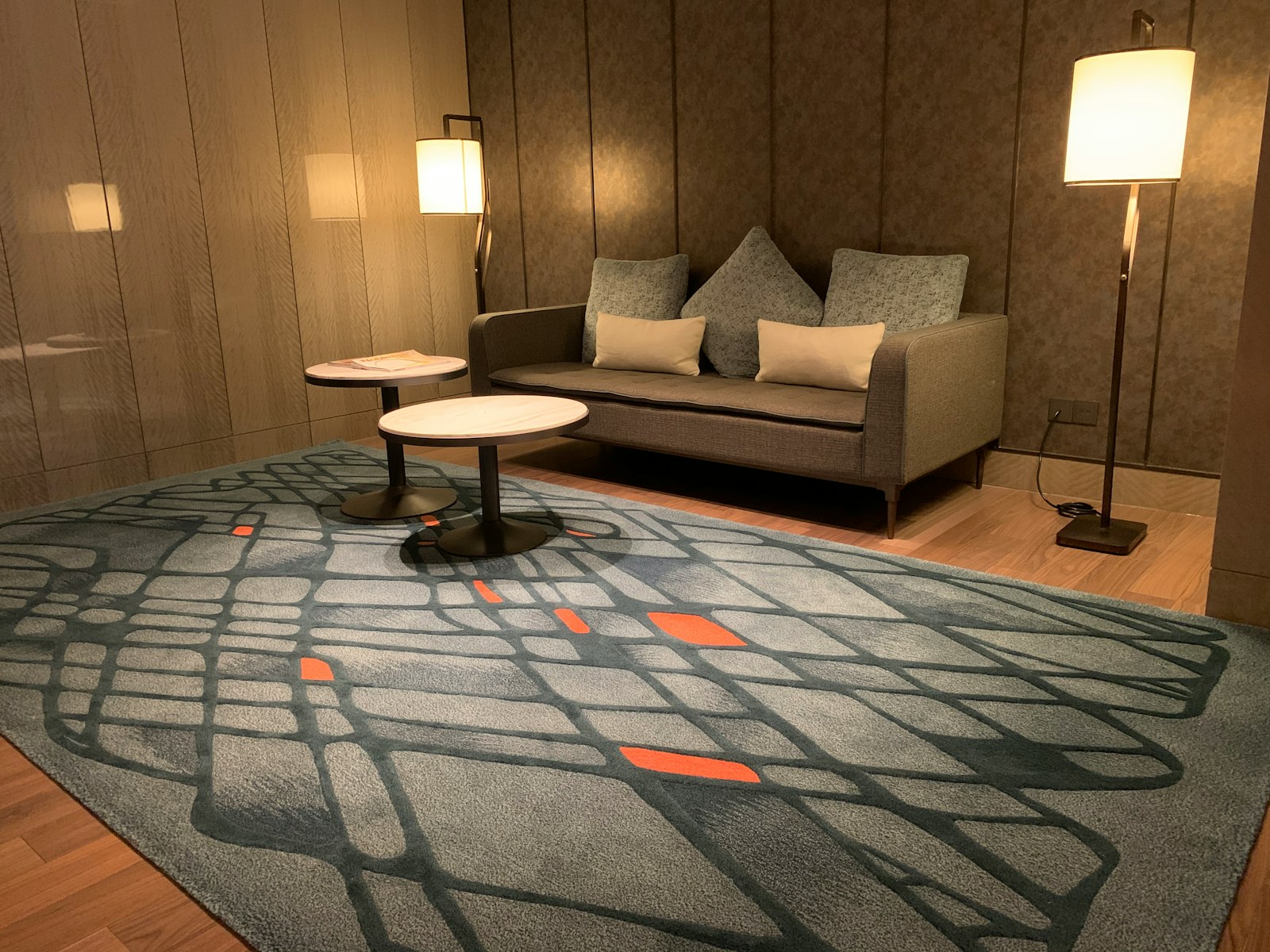 two round white tables beside sofa between floor lamps